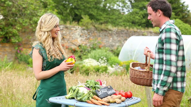Handsome man buying peppers from smiling gardener