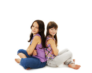 Portrait of a two little girls sitting back to back and smiling