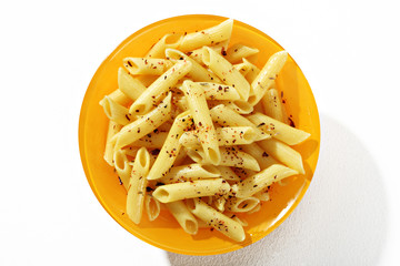 Looking down at a plate of cooked penne pasta with spices