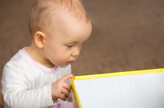 Baby schaut neugierig in die Geschenkbox