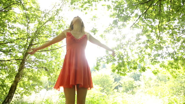 Beautiful teen twirling in the sunlight under the trees