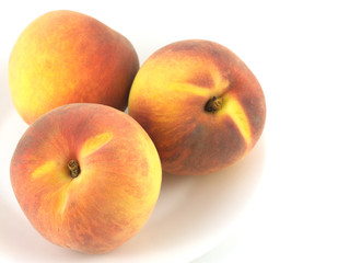 Three fresh Peaches on plate isolated on white close up