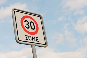 Schild - 30 km Zone - vor blauem Himmel mit weissen Wolken