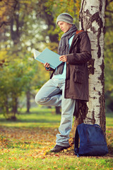 Young male student reading a book in a park