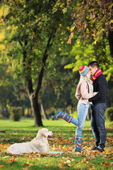 Obraz premium Male and female kissing in a park and a dog watching them