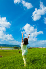 青空に向かって手を広げる一人の女性