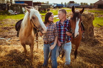 couple standing on farm with horses