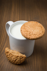 mug of milk and oat cookies on a wooden background