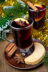 two glasses of mulled wine with spices in glass and cookies
