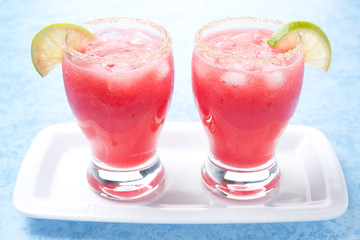 glasses of watermelon cocktail with brown sugar, lime on plate