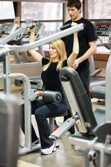 Woman with her personal fitness trainer in the gym