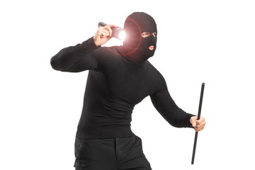 Robber with robbery mask holding a flashlight and piece of pipe