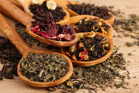 Fototapeta assortment of dry tea in spoons, on wooden background