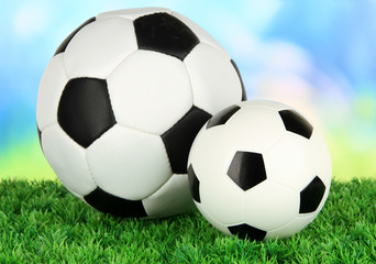 Soccer balls on green grass on bright background