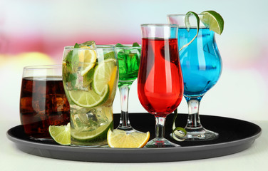 Many glasses of cocktails on tray on table, on bright