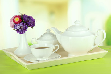 Cup of tea with cakes on wooden tray on table in room