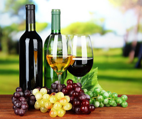 Obraz na płótnie Canvas Wine bottles and glasses of wine on bright background