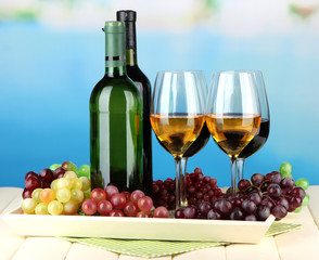 Fototapeta premium Wine bottles and glasses of wine on tray, on bright background