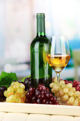 Wine bottle and glass of wine on tray, on bright background