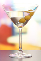 Martini with green olives on table in bar