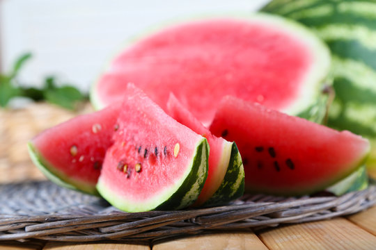 Ripe watermelons on wicker tray  on table on wooden background