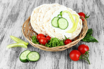 Tasty crispbreads with vegetables on wooden background