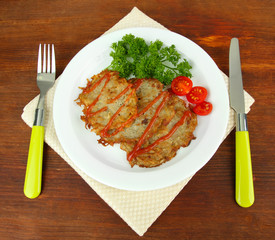 Potato pancakes on plate, on wooden background