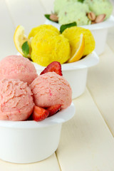 Tasty ice cream scoops in bowls, on wooden table