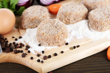 Meat patties on board on wooden table