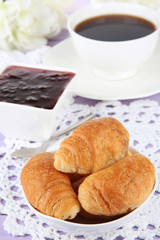 Tasty croissants and cup of coffee on table close-up