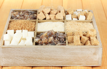 Different types of sugar in wooden box on table close-up