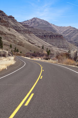 Naklejka premium Lonely Two Lane Divided Highway Cuts Through Dry Landscape