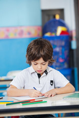 Naklejka premium Boy With Sketch Pens Drawing In Kindergarten