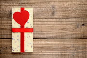 White chocolate with ribbon and red heart on wooden background