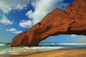 Amazing view of huge red cliffs with arch on the beach Legzira