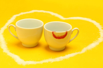 Two cups of coffee inside a heart, one of them with lipstick