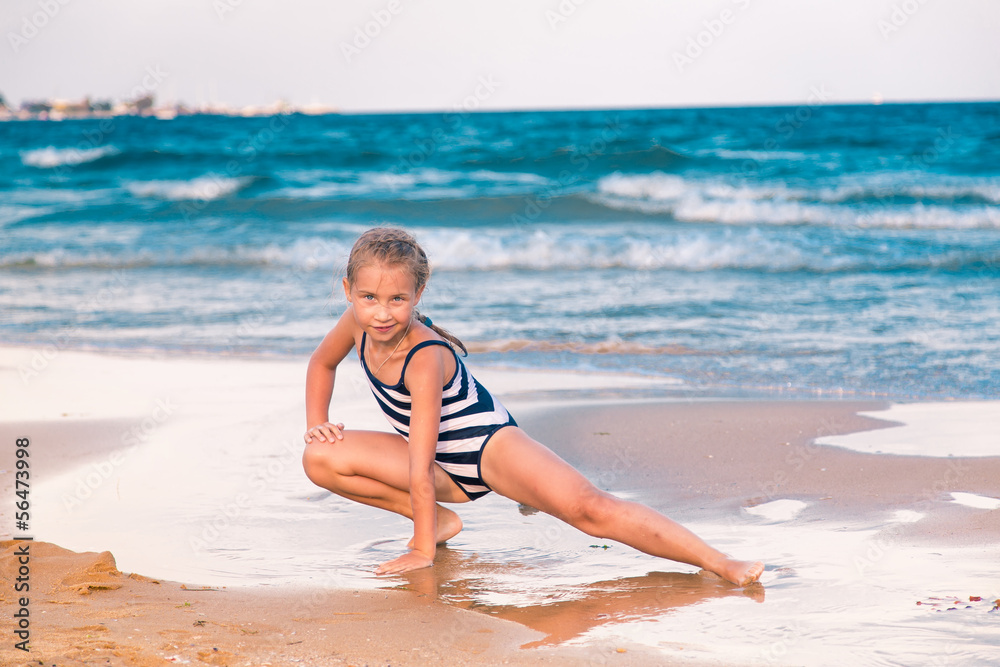 Wall mural beautiful little girl excercising on the beach