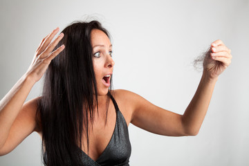 Hübsche Frau guckt schockiert auf ihre Haarbürste