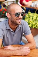 Positive middle-aged man alone  in summer cafe