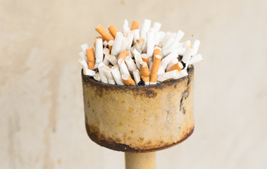 dirty ashtray with cigarette ash and butts