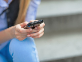 Closeup on hipster girl writing sms while sitting on stairs