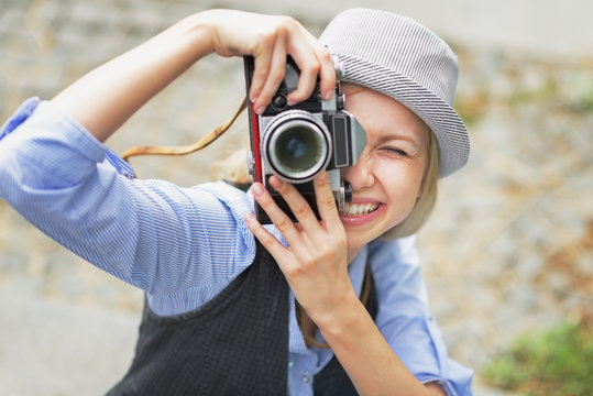 Smiling hipster girl making photo with retro camera