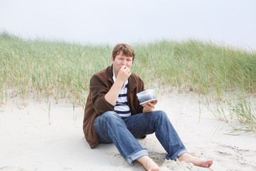 Fototapeta premium Young happy man relaxing on sand dunes of the beach of St.Peter