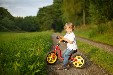 Little toddler boy learning to ride on his first bike