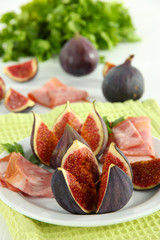 Tasty figs with ham on white wooden table