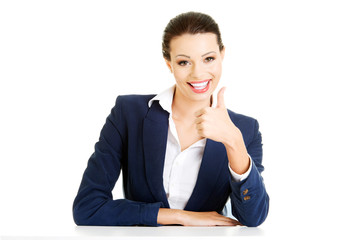 Young woman at the desk gesturing OK