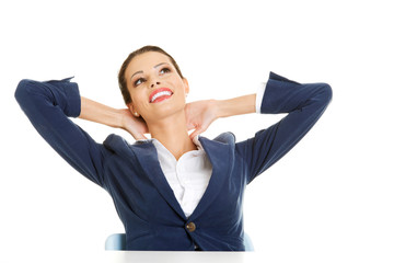 Female executive relaxing with hands behind head