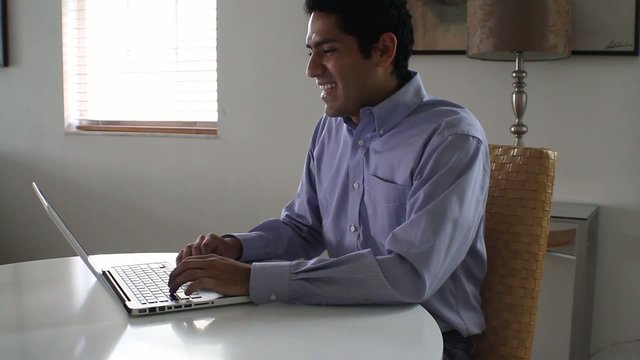 Businessman laughing while chatting on a laptop.