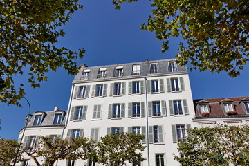 Façade blanche, ciel bleu, arbres verts.