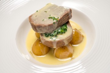 Two pieces of meat with potato and sauce